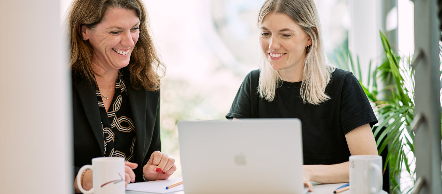 Zwei Mitarbeiterinnen des Weltethos-Instituts sitzen zusammen und arbeiten